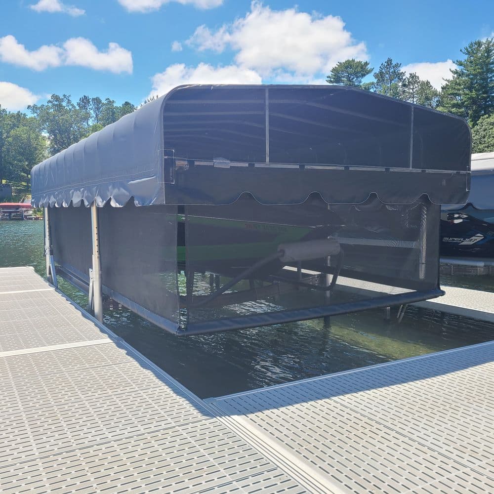Covered boat dock on a sunny day with blue skies and calm water reflections.
